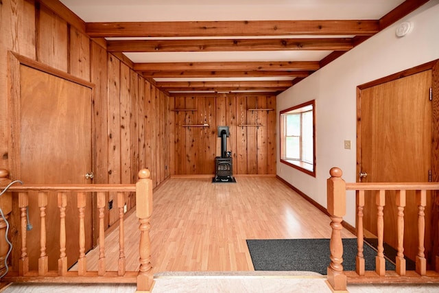 919 Howard St, Winona, MN 55987 - interior space with a wood stove, beamed ceiling, light wood-style floors, wood walls, and baseboards