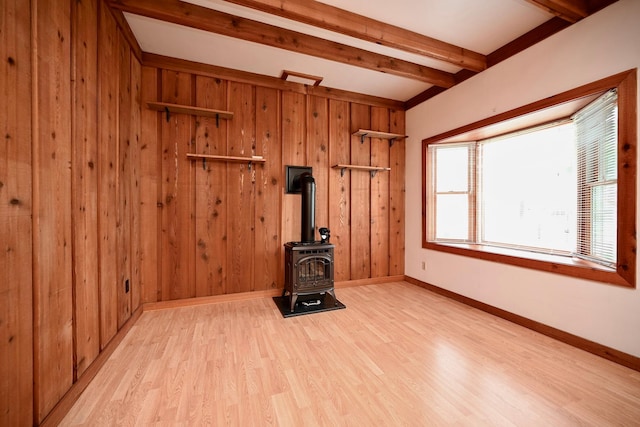 919 Howard St, Winona, MN 55987 - unfurnished living room featuring beamed ceiling, a wood stove, light wood-type flooring, baseboards, and wooden walls