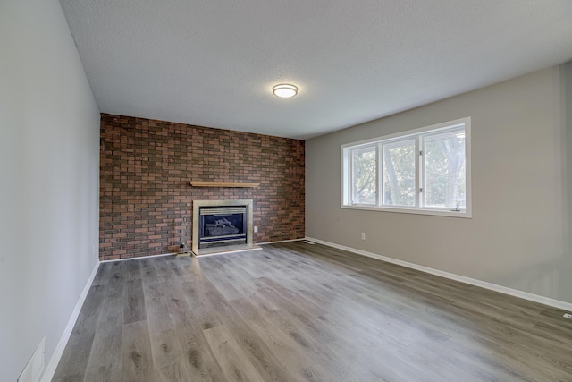4207 Fillmore St NE, Columbia Heights, MN 55421 - unfurnished living room featuring baseboards, a textured ceiling, wood finished floors, a fireplace, and brick wall