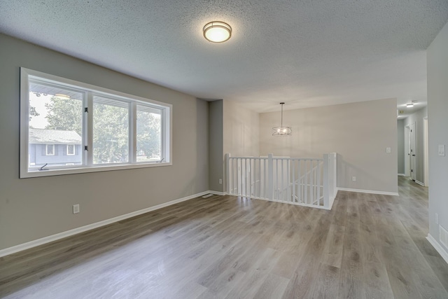 4207 Fillmore St NE, Columbia Heights, MN 55421 - unfurnished room featuring wood finished floors, a textured ceiling, baseboards, and a chandelier
