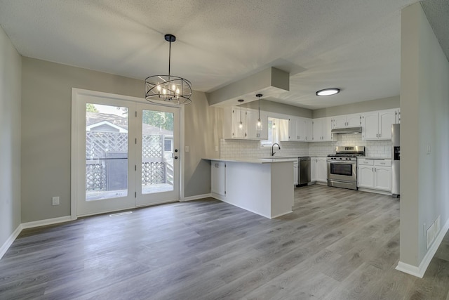4207 Fillmore St NE, Columbia Heights, MN 55421 - kitchen with appliances with stainless steel finishes, a peninsula, under cabinet range hood, a chandelier, and decorative backsplash