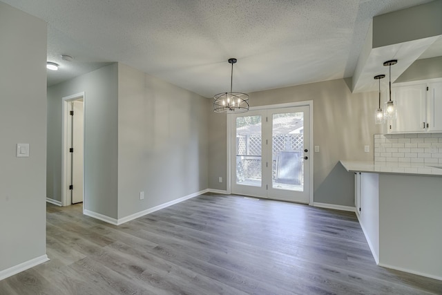 4207 Fillmore St NE, Columbia Heights, MN 55421 - unfurnished dining area with a chandelier, a textured ceiling, light wood-style floors, and baseboards