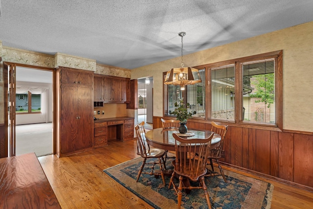 4017 Kentucky Ave N, Crystal, MN 55427 - dining room featuring light wood finished floors, a textured ceiling, wainscoting, a chandelier, and wooden walls