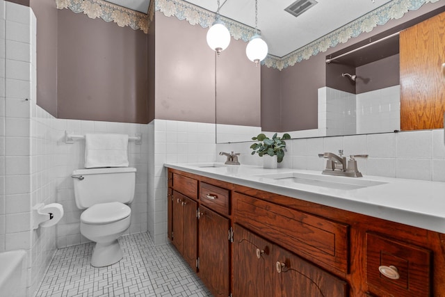 4017 Kentucky Ave N, Crystal, MN 55427 - bathroom featuring toilet, double vanity, tile walls, a wainscoted wall, and tile patterned floors