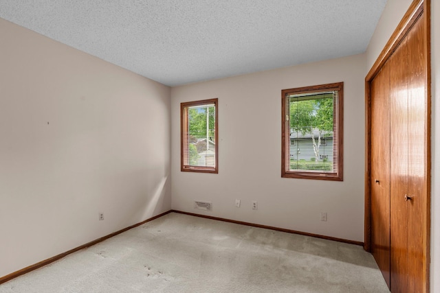 4017 Kentucky Ave N, Crystal, MN 55427 - unfurnished bedroom with multiple windows, light carpet, a closet, baseboards, and a textured ceiling