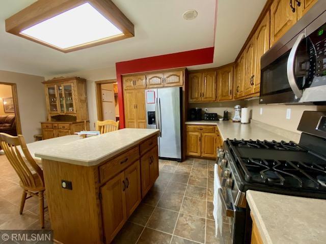 23110 Grandview Loop, Long Prairie Twp, MN 56347 - kitchen featuring appliances with stainless steel finishes, brown cabinets, a kitchen island, light countertops, and a kitchen bar