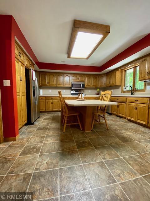 23110 Grandview Loop, Long Prairie Twp, MN 56347 - kitchen with stainless steel appliances, light countertops, brown cabinets, and a breakfast bar area
