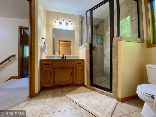 23110 Grandview Loop, Long Prairie Twp, MN 56347 - bathroom featuring toilet, a shower stall, tile patterned floors, vanity, and baseboards