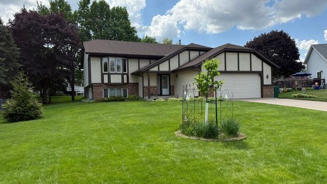 656 Mina Ct, Mahtomedi, MN 55082 - tudor house with driveway, an attached garage, brick siding, and a front yard