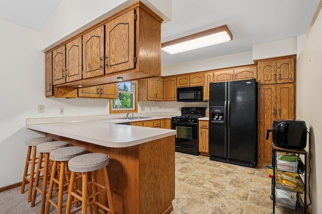 656 Mina Ct, Mahtomedi, MN 55082 - kitchen featuring black appliances, a peninsula, brown cabinetry, light countertops, and light stone finish flooring