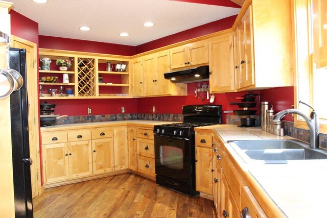 1729 Quail Ln NE, Longville, MN 56655 - kitchen featuring under cabinet range hood, black appliances, a sink, tile counters, and light brown cabinetry