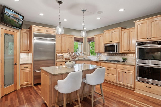 9885 Troy Ln N, Maple Grove, MN 55311 - kitchen with light brown cabinetry, appliances with stainless steel finishes, decorative backsplash, light stone countertops, and a kitchen island