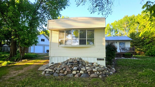 33798 Shady Oak Dr, Foster Twp, MN 56225 - view of property exterior featuring a deck, an outbuilding, a lawn, and a garage