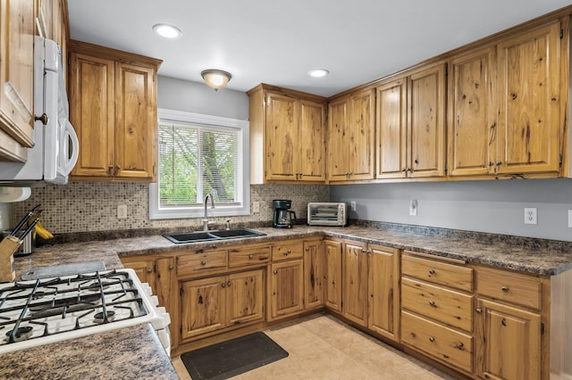 3364 85th Ave, Princeton, MN 55371 - kitchen with a sink, brown cabinetry, dark countertops, backsplash, and white appliances