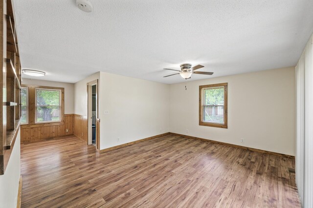 3364 85th Ave, Princeton, MN 55371 - spare room with wood finished floors, plenty of natural light, ceiling fan, wainscoting, and a textured ceiling
