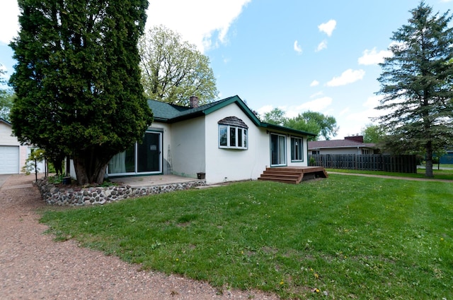 915 Knapp St, Rice Lake, WI 54868 - rear view of house with stucco siding, a chimney, a garage, and an outbuilding