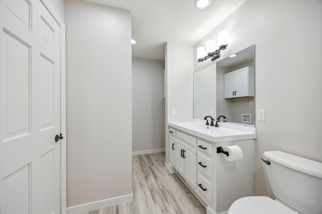 67854 217th St, Darwin, MN 55324 - half bath featuring vanity, toilet, wood finished floors, and baseboards