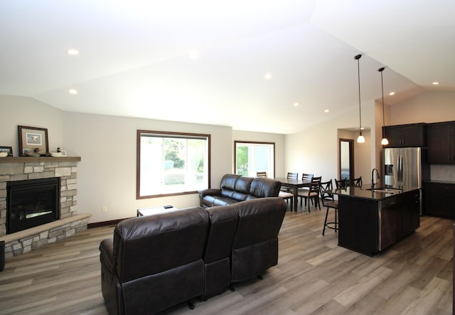 1707 17th St NW, Willmar, MN 56201 - living area featuring lofted ceiling, light wood-style floors, a stone fireplace, and recessed lighting