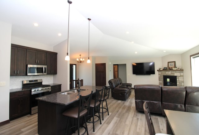 1707 17th St NW, Willmar, MN 56201 - kitchen with appliances with stainless steel finishes, lofted ceiling, a kitchen breakfast bar, a sink, and dark brown cabinets
