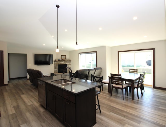 1707 17th St NW, Willmar, MN 56201 - kitchen featuring a sink, dishwasher, a breakfast bar area, a stone fireplace, and a kitchen island with sink