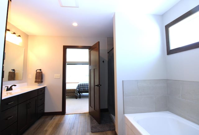 1707 17th St NW, Willmar, MN 56201 - full bathroom featuring connected bathroom, wood finished floors, a bath, vanity, and baseboards