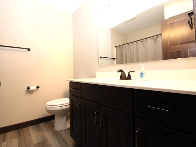 1707 17th St NW, Willmar, MN 56201 - full bathroom with toilet, wood finished floors, vanity, and baseboards