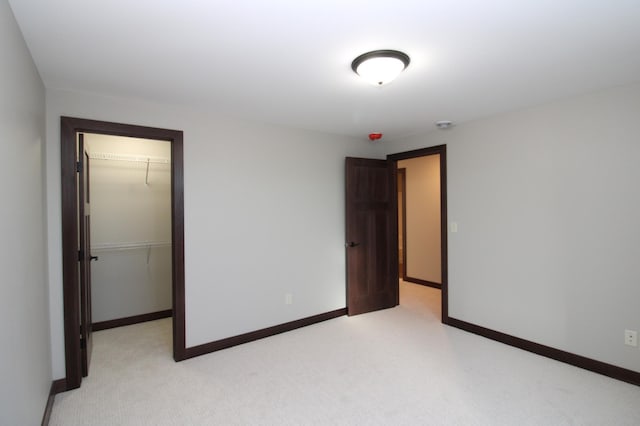 1707 17th St NW, Willmar, MN 56201 - unfurnished bedroom with a walk in closet, light carpet, a closet, and baseboards
