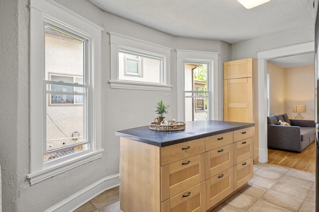 3545 Minnehaha Ave, Minneapolis, MN 55406 - kitchen with light brown cabinets, dark countertops, baseboards, a textured ceiling, and light tile patterned floors