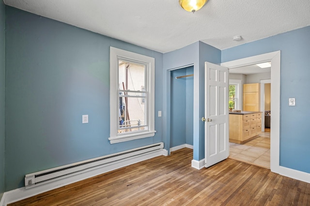 3545 Minnehaha Ave, Minneapolis, MN 55406 - unfurnished bedroom with baseboard heating, baseboards, wood finished floors, a closet, and a textured ceiling