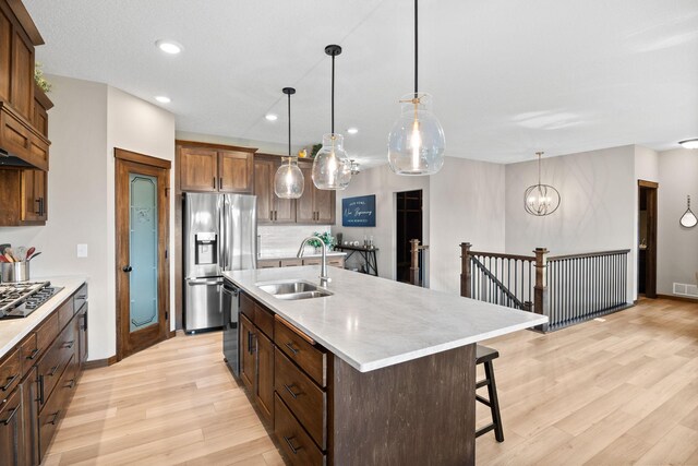 249 3rd St SW, Delano, MN 55328 - kitchen featuring black appliances, light wood-style floors, light countertops, a sink, and a breakfast bar