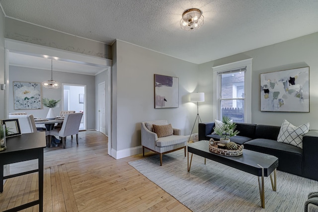 1066 Reaney Ave, Saint Paul, MN 55106 - living room with light wood-style flooring, baseboards, a textured ceiling, a chandelier, and crown molding