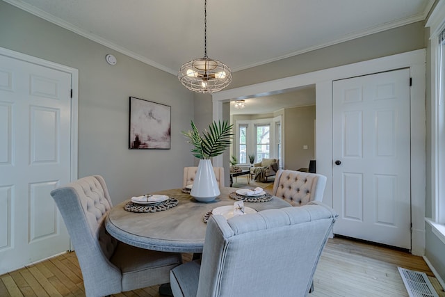 1066 Reaney Ave, Saint Paul, MN 55106 - dining room with light wood finished floors, crown molding, and a chandelier