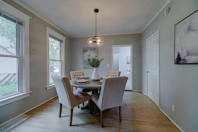 1066 Reaney Ave, Saint Paul, MN 55106 - dining area with light wood-style floors, crown molding, a chandelier, baseboards, and a textured ceiling
