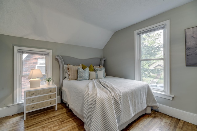 1066 Reaney Ave, Saint Paul, MN 55106 - bedroom featuring vaulted ceiling, wood-type flooring, multiple windows, and baseboards