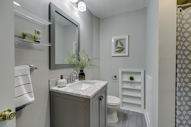 1066 Reaney Ave, Saint Paul, MN 55106 - bathroom featuring toilet, vanity, a textured ceiling, a shower with shower curtain, and wood finished floors