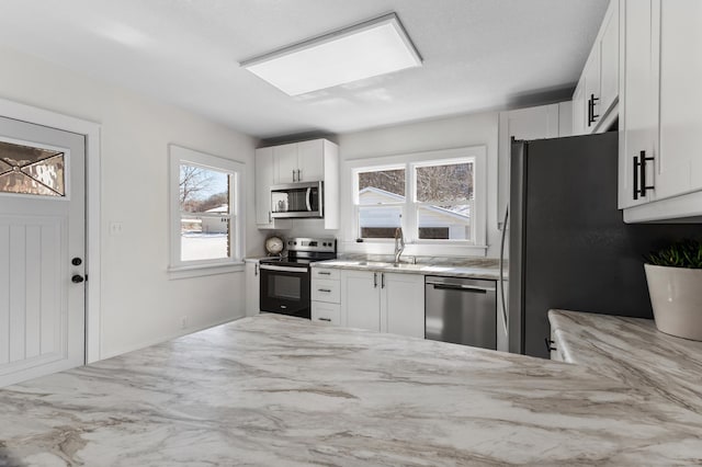 781 7th St, Red Wing, MN 55066 - kitchen featuring stainless steel appliances, light stone countertops, a sink, and white cabinetry