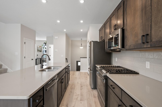 7602 Connie Ln, Inver Grove Heights, MN 55076 - kitchen featuring stainless steel appliances, a sink, light wood finished floors, dark brown cabinetry, and tasteful backsplash