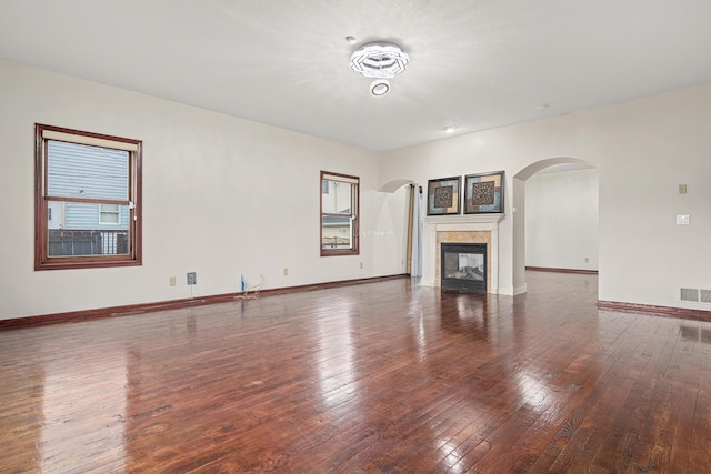 338 Aurora Ave, Saint Paul, MN 55103 - unfurnished living room featuring arched walkways, hardwood / wood-style floors, baseboards, and a tile fireplace