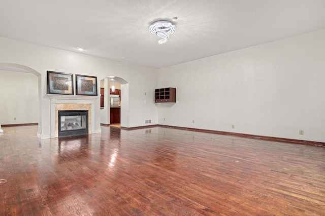 338 Aurora Ave, Saint Paul, MN 55103 - unfurnished living room with wood finished floors, arched walkways, baseboards, and a fireplace
