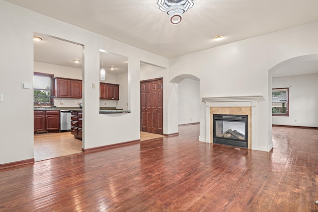 338 Aurora Ave, Saint Paul, MN 55103 - unfurnished living room featuring wood finished floors, a fireplace, arched walkways, and baseboards