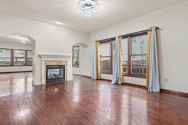 338 Aurora Ave, Saint Paul, MN 55103 - unfurnished living room featuring hardwood / wood-style floors, arched walkways, a tiled fireplace, and baseboards