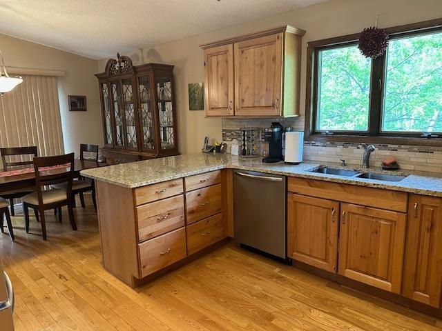 26722 Eisenmen Dr, Leonard, MN 56652 - kitchen with dishwasher, a sink, a peninsula, light wood-style floors, and vaulted ceiling