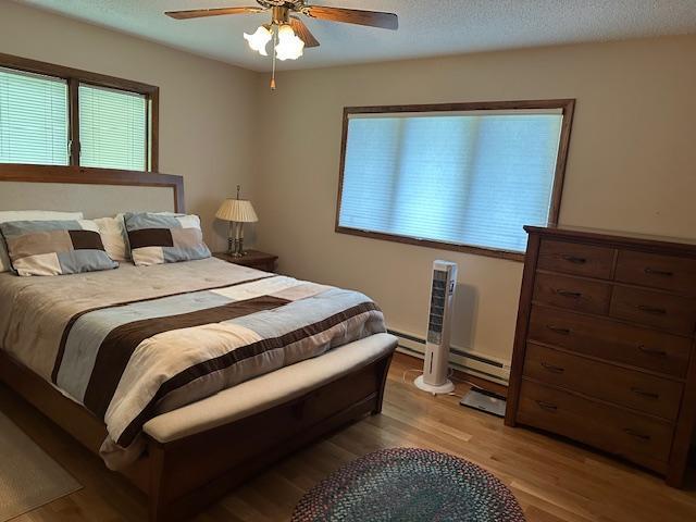 26722 Eisenmen Dr, Leonard, MN 56652 - bedroom with light wood-type flooring, ceiling fan, and baseboard heating