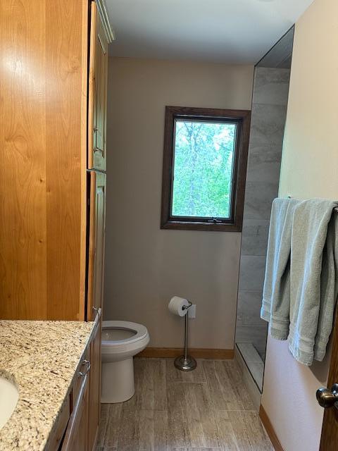 26722 Eisenmen Dr, Leonard, MN 56652 - full bathroom with vanity, walk in shower, toilet, baseboards, and wood finished floors