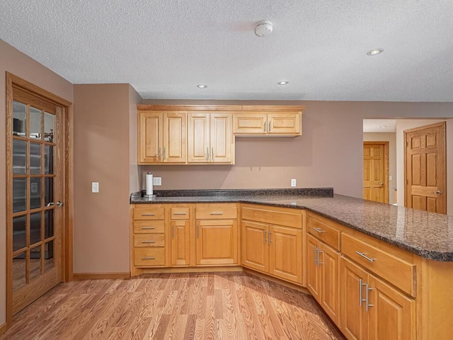 9368 188th Ave NW, Nowthen, MN 55330 - kitchen with light wood-type flooring, a textured ceiling, a peninsula, dark stone counters, and recessed lighting