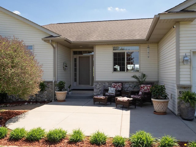 9368 188th Ave NW, Nowthen, MN 55330 - property entrance featuring a patio, roof with shingles, outdoor lounge area, and stone siding