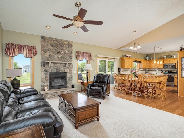 9368 188th Ave NW, Nowthen, MN 55330 - living room with a ceiling fan, vaulted ceiling, a fireplace, light wood finished floors, and a chandelier