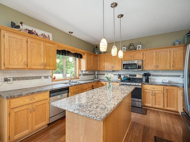 9368 188th Ave NW, Nowthen, MN 55330 - kitchen with appliances with stainless steel finishes, a kitchen island, dark wood finished floors, light stone counters, and hanging light fixtures