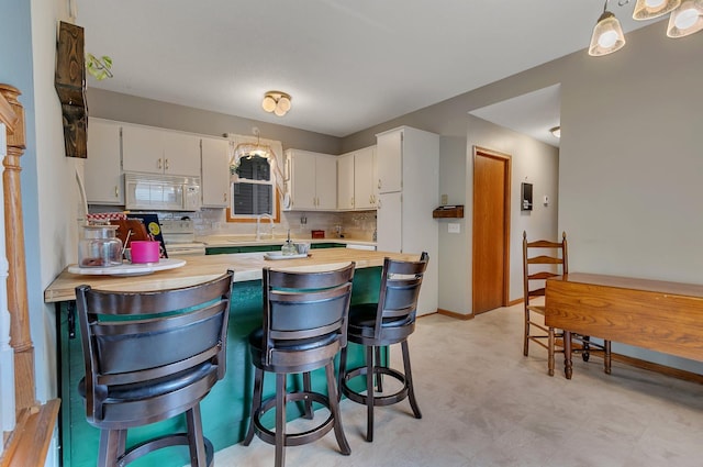 215 Main St E, Freeport, MN 56331 - kitchen with white appliances, a peninsula, light flooring, backsplash, and white cabinetry