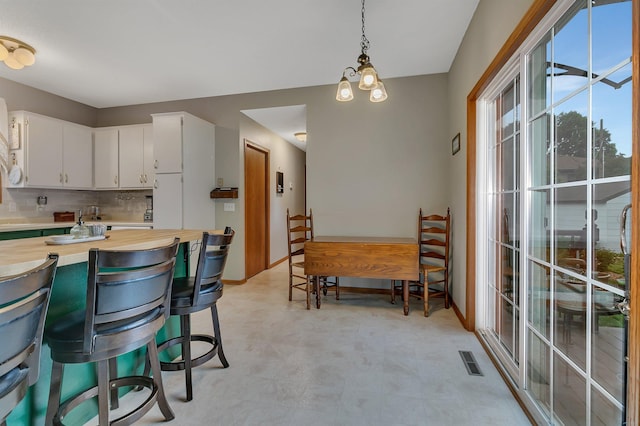 215 Main St E, Freeport, MN 56331 - kitchen featuring wood counters, light floors, white cabinets, pendant lighting, and decorative backsplash
